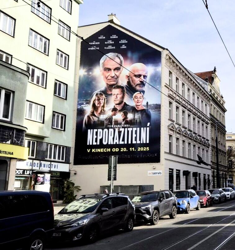 Velkoformátová plachta filmu Neporazitelní přes celou stěnu činžovního domu v Praze